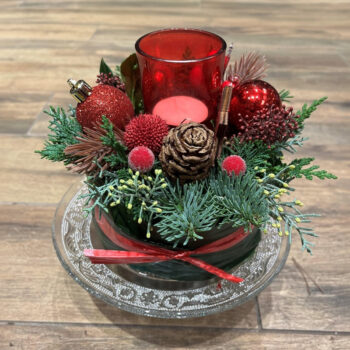 Rode kersttaart met wintergroen, rode kerstballen en een rood waxinelichthouder