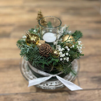 Witte kersttaart met wintergroen, gouden kerstballen en een glaasje voor een waxinelichtje